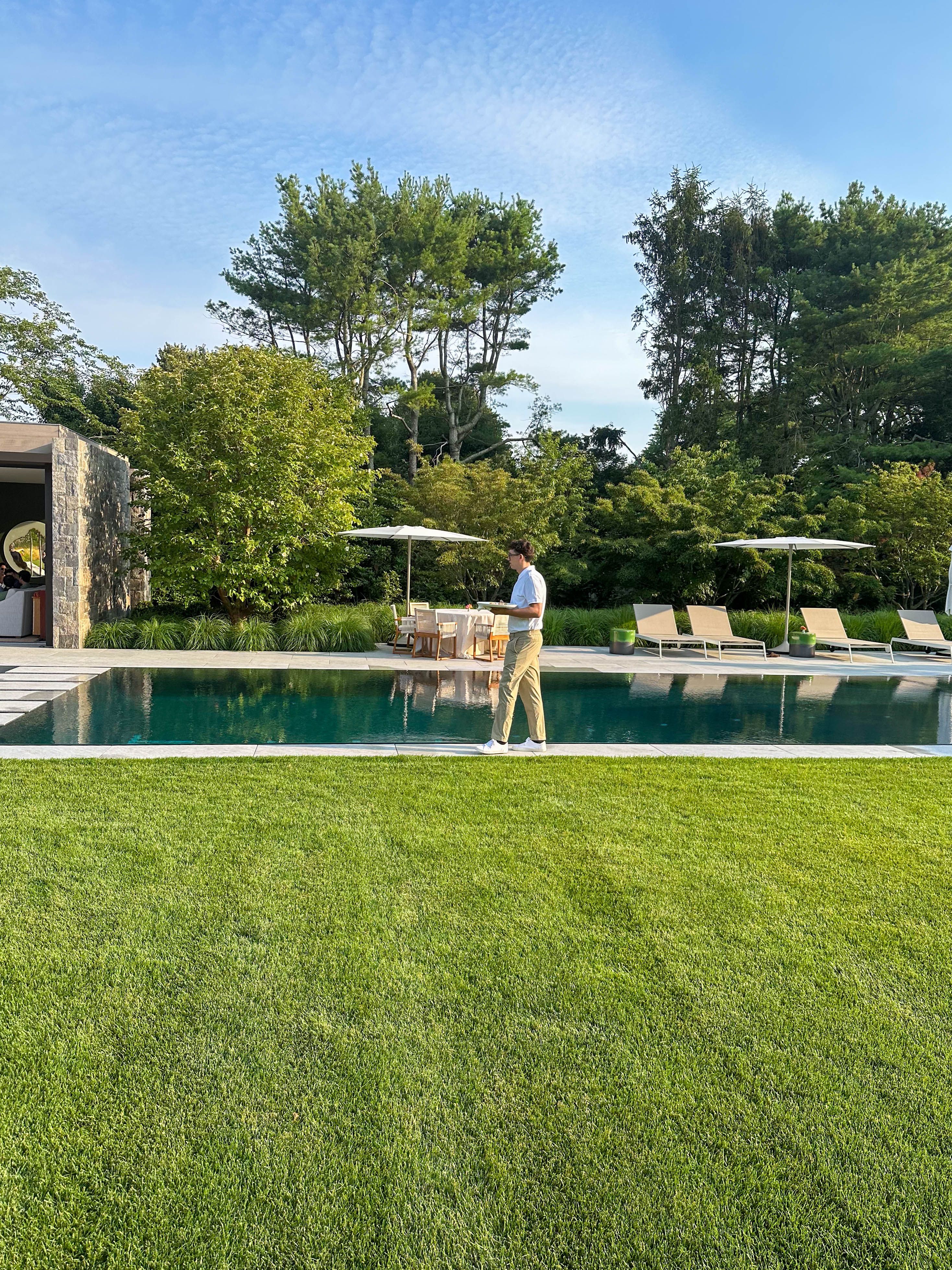 Catering staff walking beside a luxury pool preparing to serve guests at an outdoor private event.