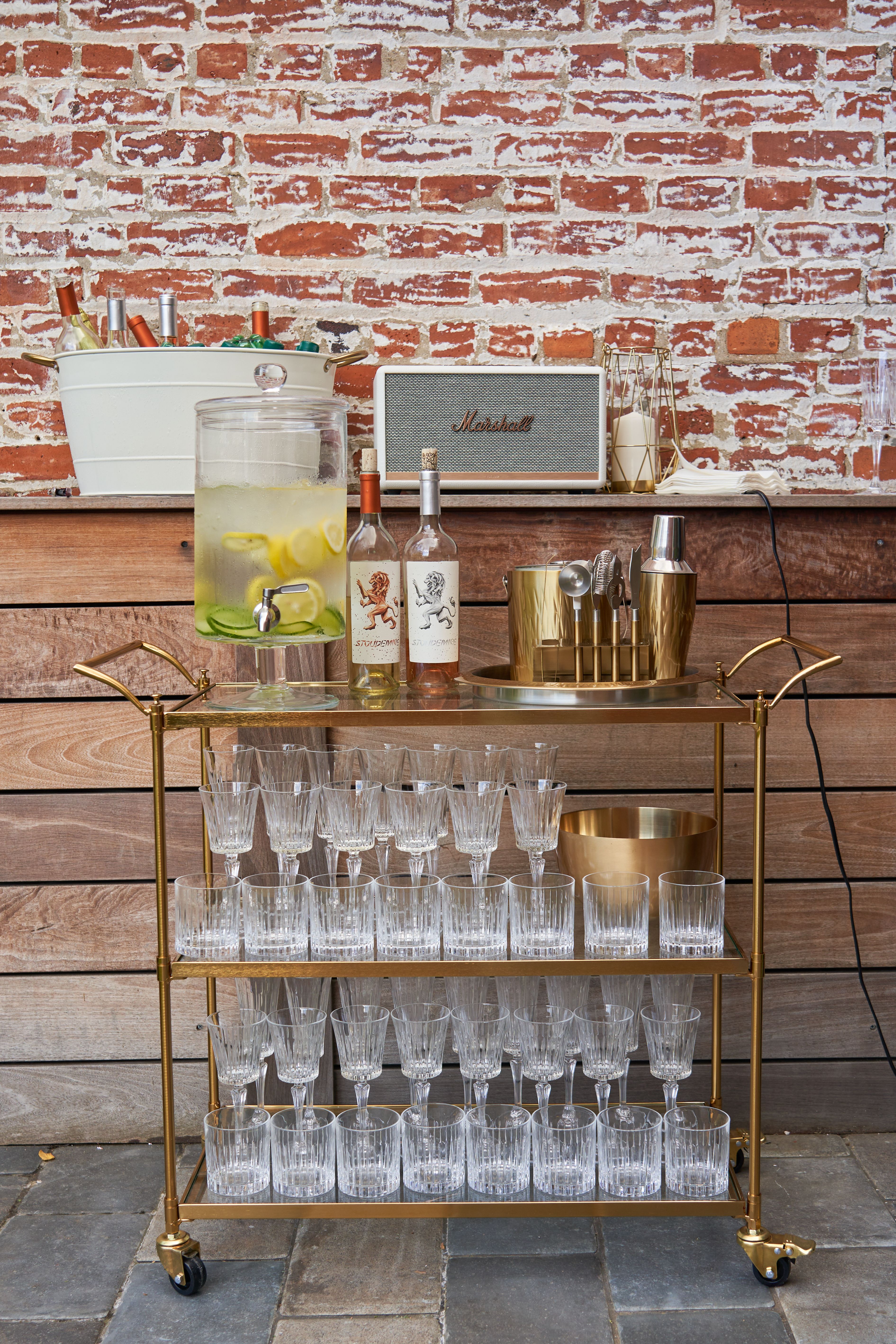 Mobile bar cart with cocktail tools, glassware, and infused water set up for an event bar service.