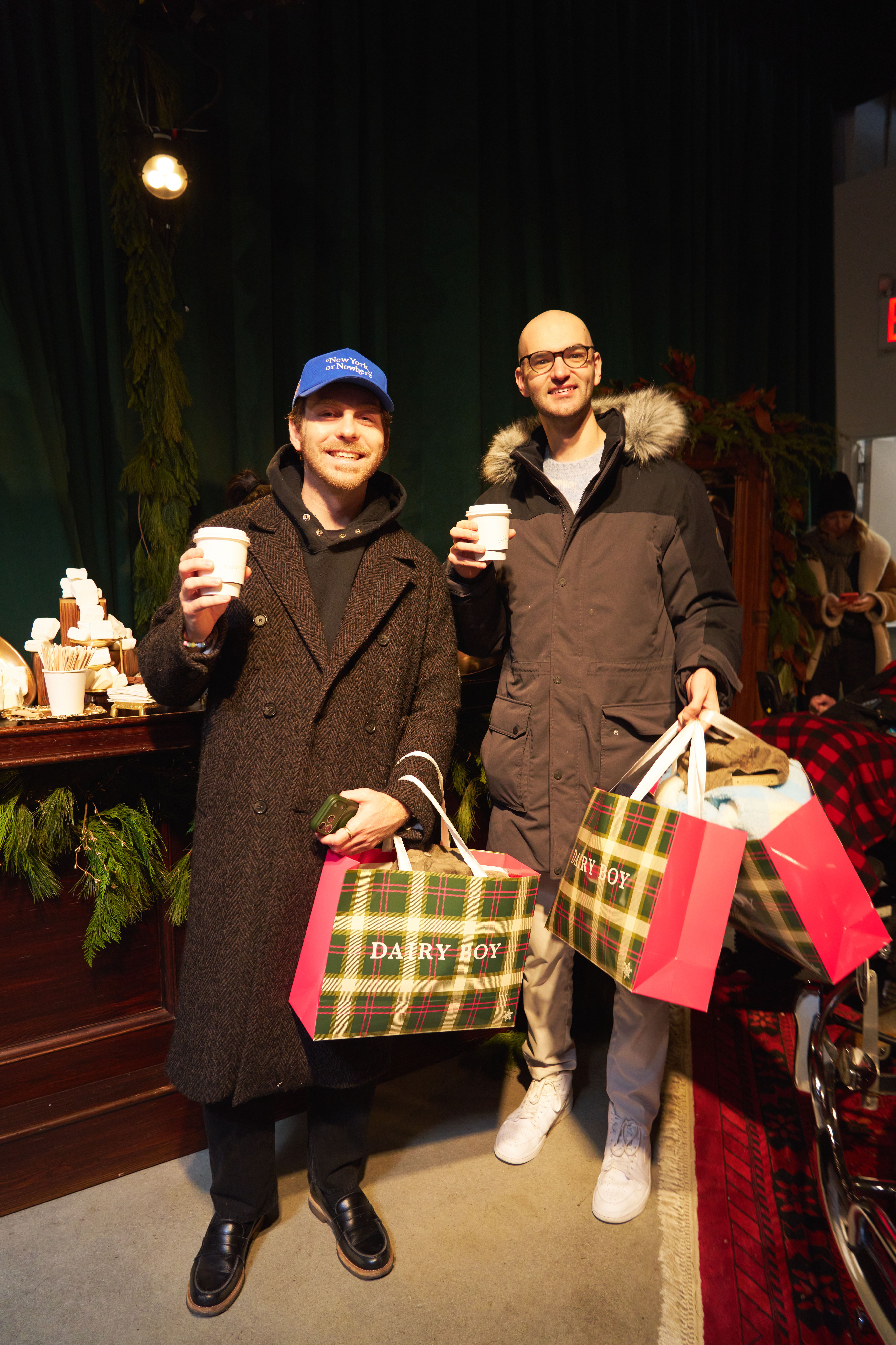 Guests holding hot chocolate and shopping bags during a holiday retail brand activation event.