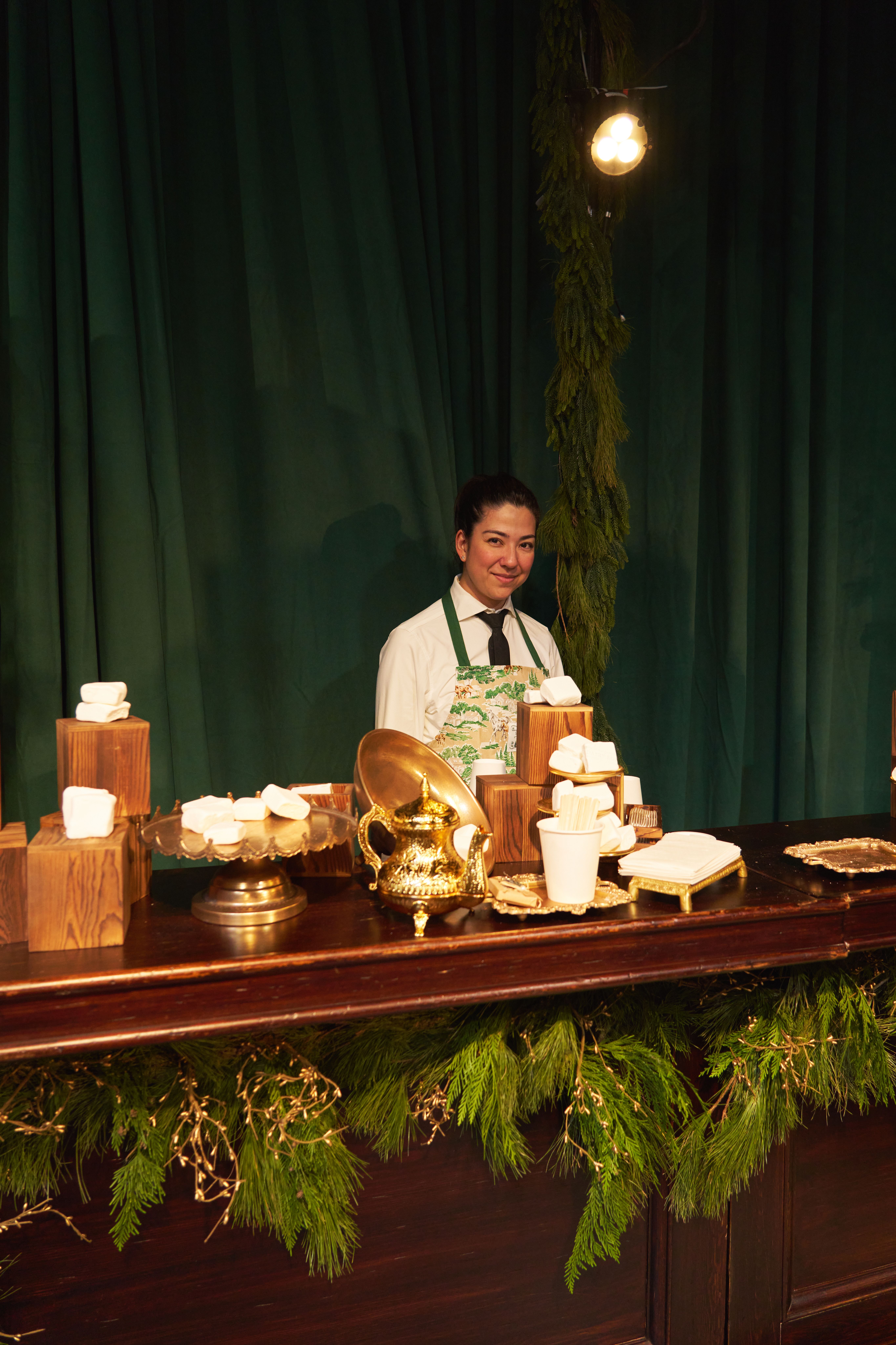 Catering staff serving a styled dessert and hot chocolate station during a holiday brand experience event.