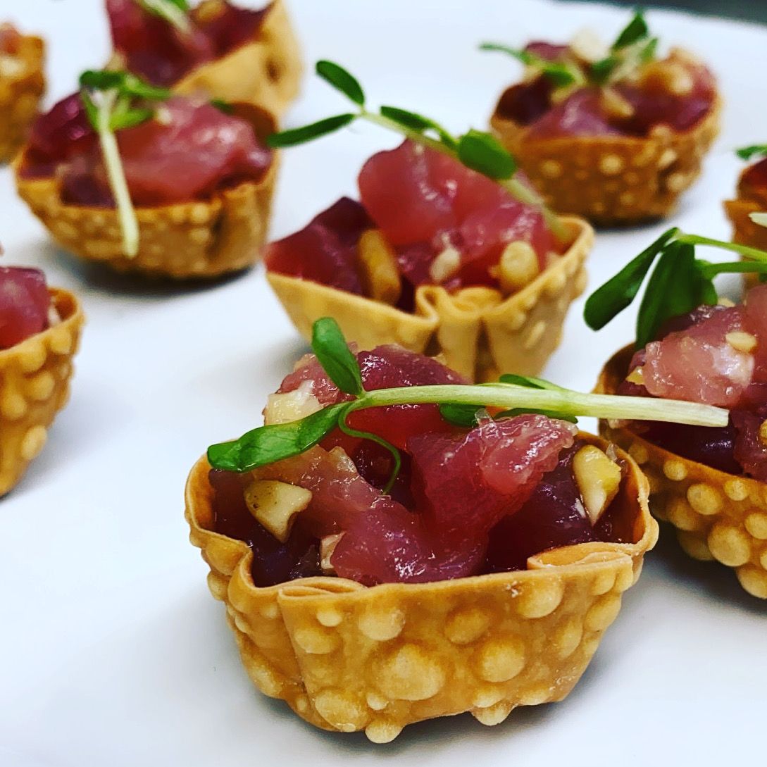 Bite-sized tuna tartare canapés served in crispy cups as passed hors d’oeuvres at a catered event.