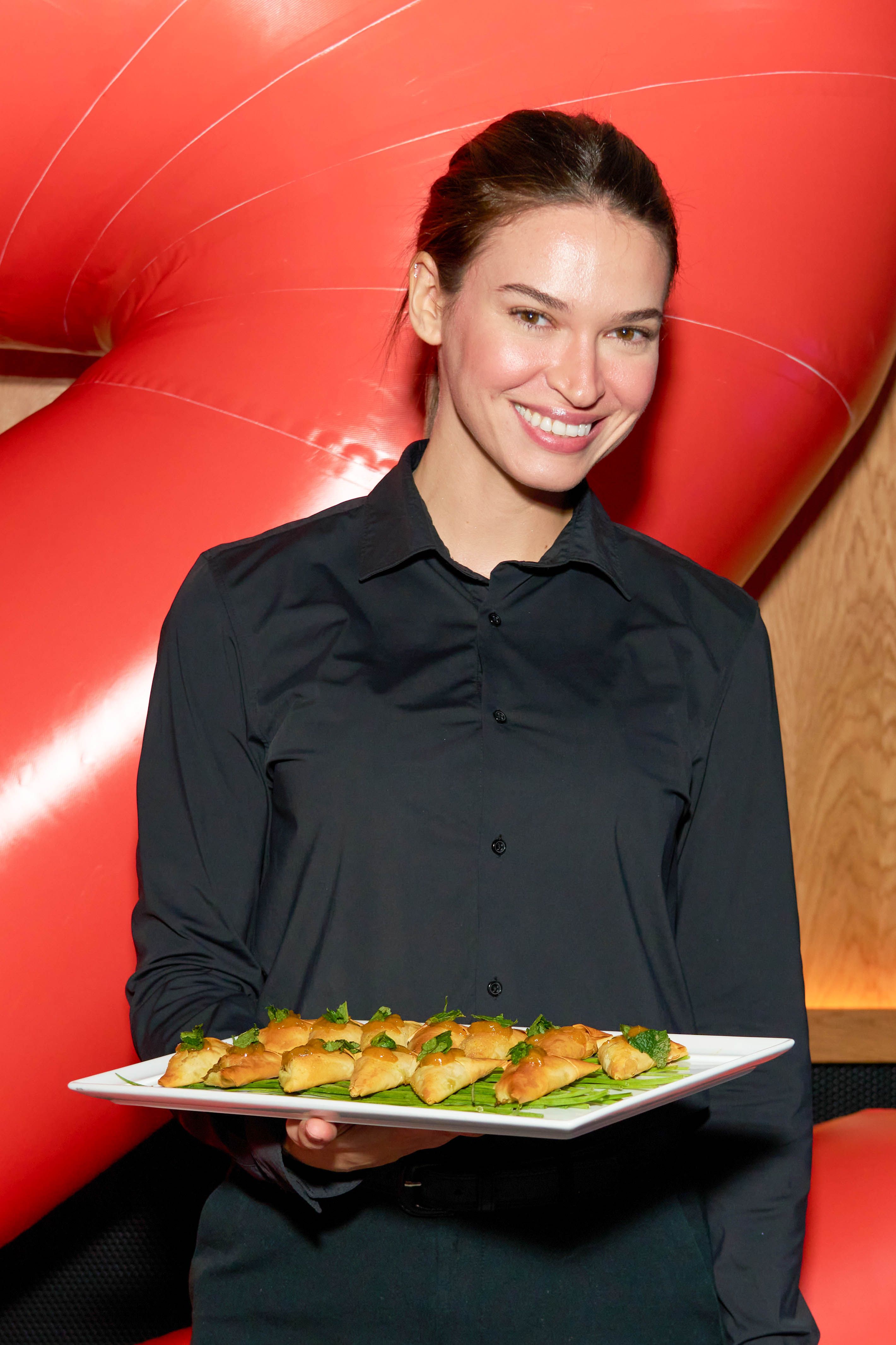 Catering server presenting a platter of passed appetizer bites during an event reception.