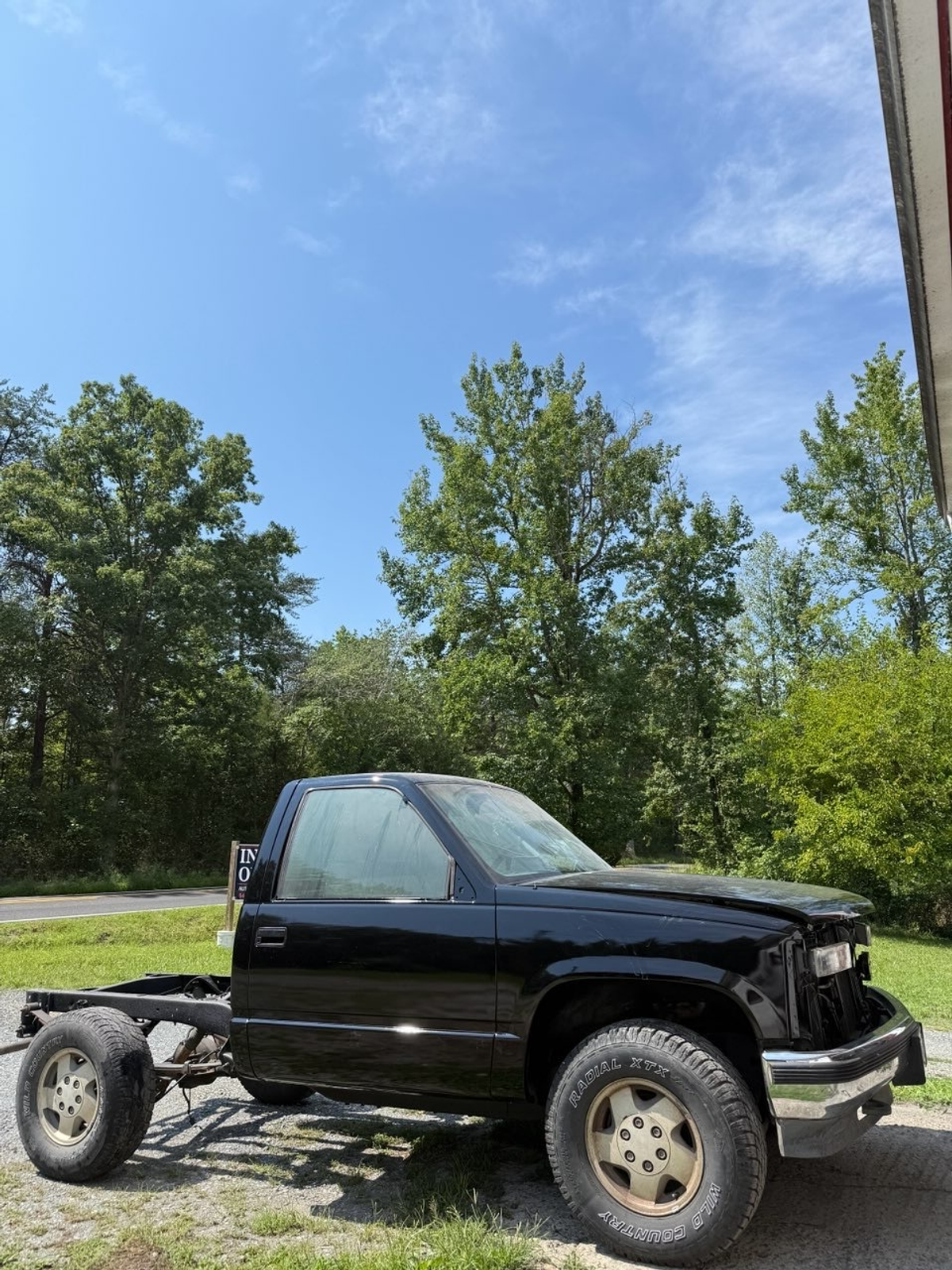 Black pickup cab mounted on its chassis outdoors during a frame-off restoration project