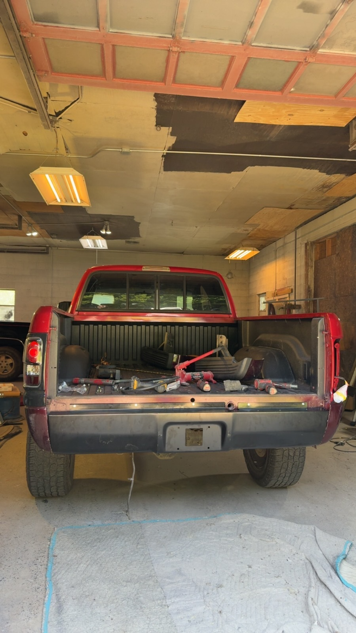 Rear view of a red pickup in the shop with the tailgate removed during body repair