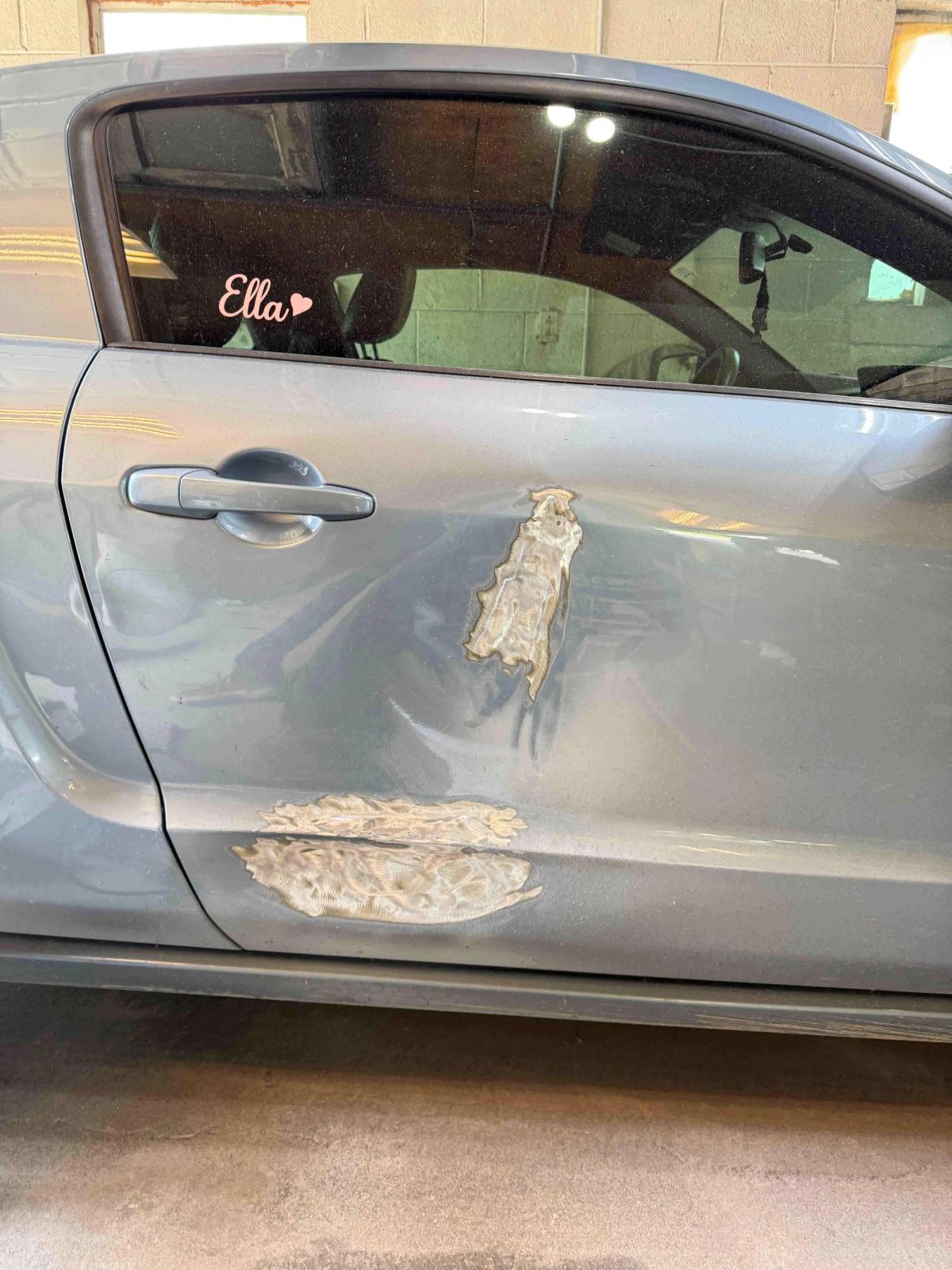 Body filler sanded smooth over a repaired car door panel before priming