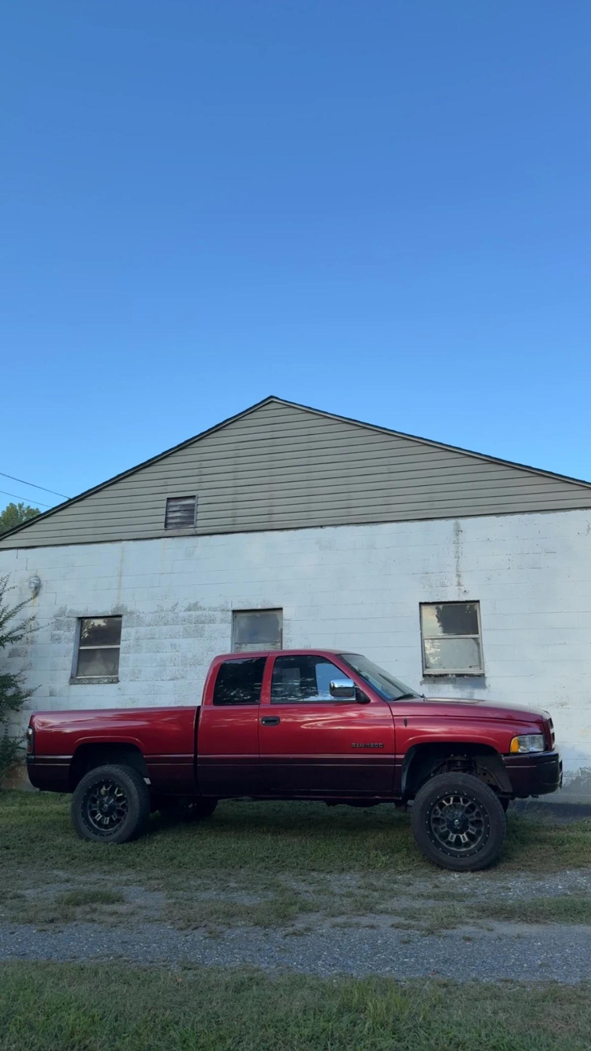 Side view of a restored two-tone red Dodge Ram pickup showing its finished body and paint