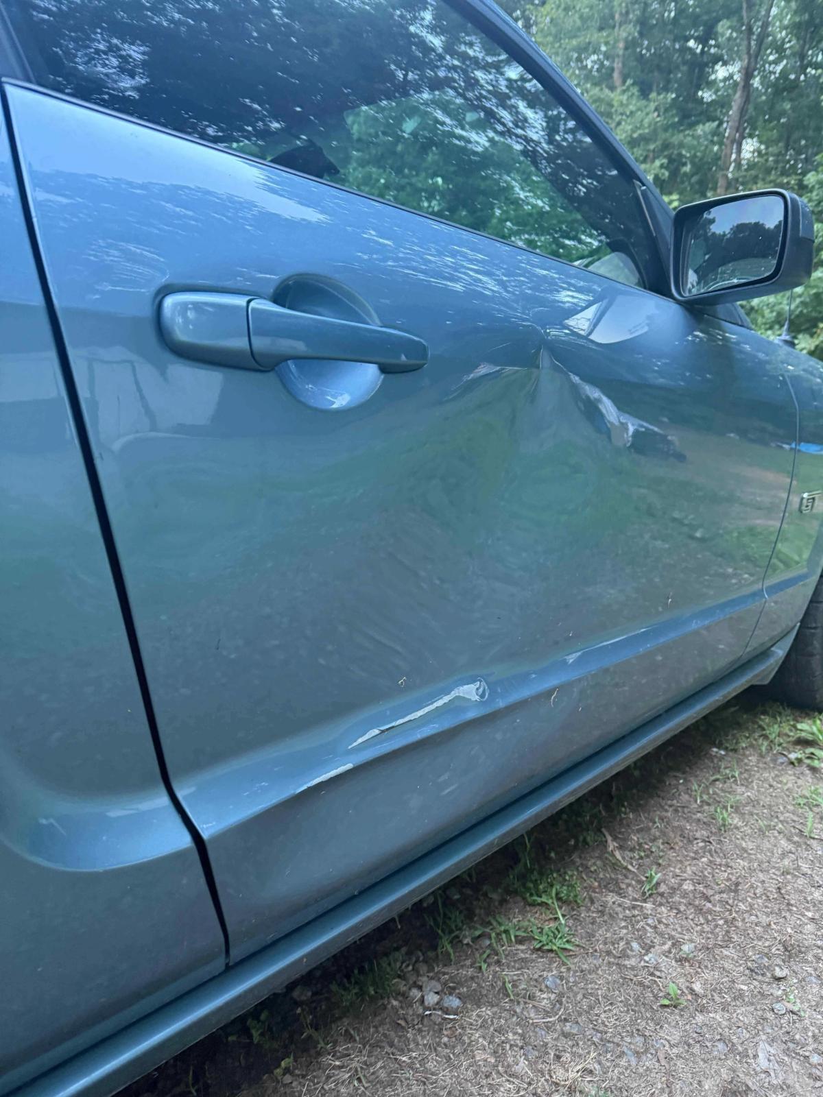 Second angle of the dented car door showing crease depth before bodywork