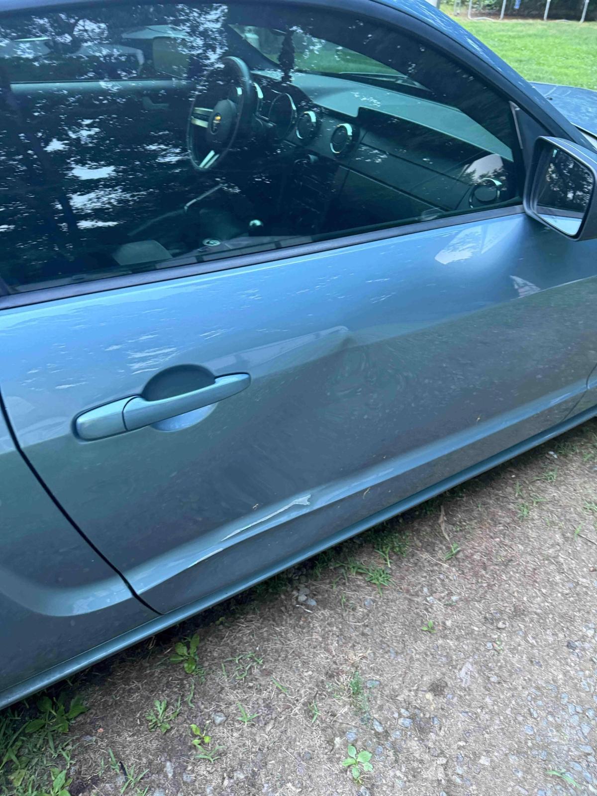 Car door with a deep dent photographed before dent repair at the Gordonsville shop
