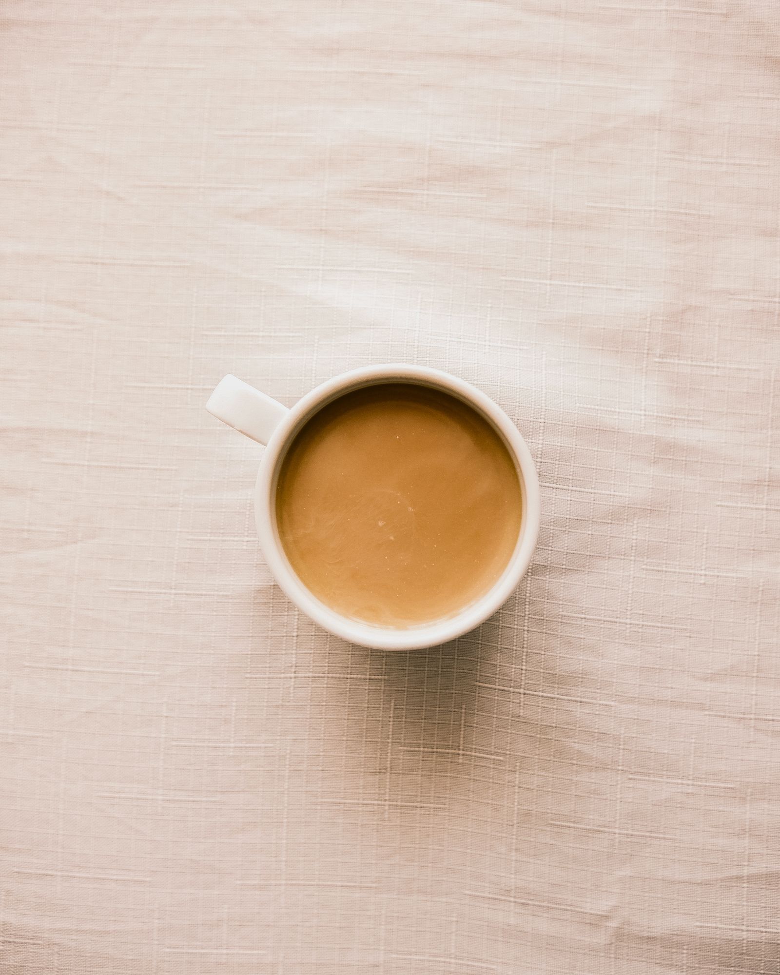 a quiet still-life — a warm cup on soft linen, neutral tones.