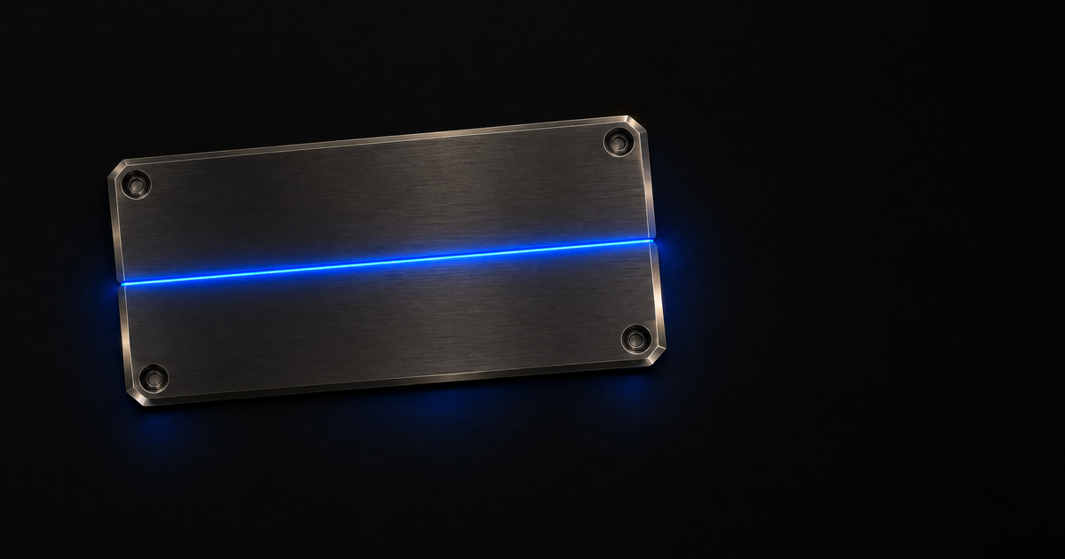 A rectangular machined dark-metal plate lies flat and closed on a black floor, seen from high overhead, its face unmarked and bolted at each corner, with one unbroken blue cobalt charge running the length of a single sealed seam and spilling onto the floor at either end.