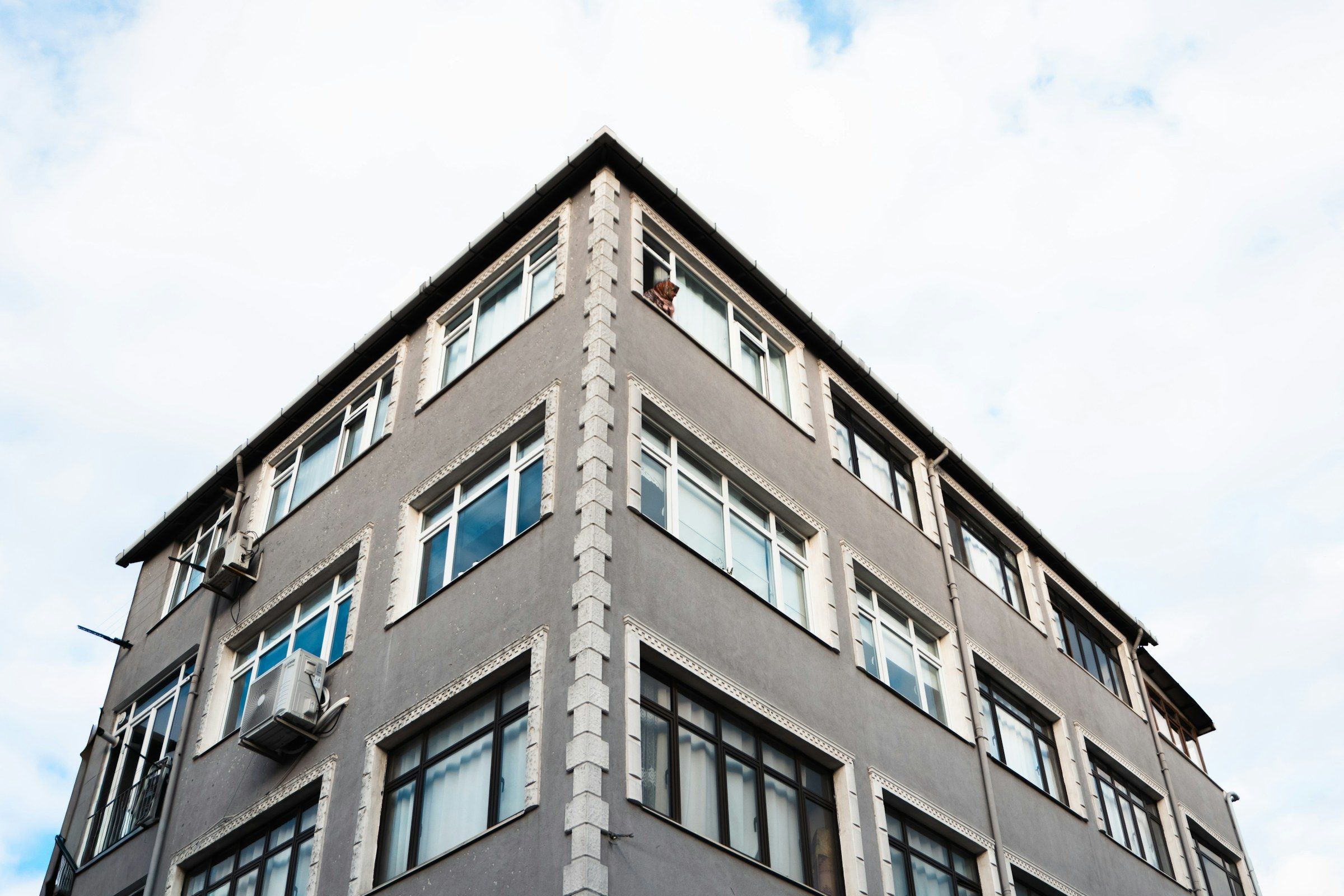 İstanbul'da çok pencereli bir apartmanın köşe cephesi, açık gökyüzüne karşı
