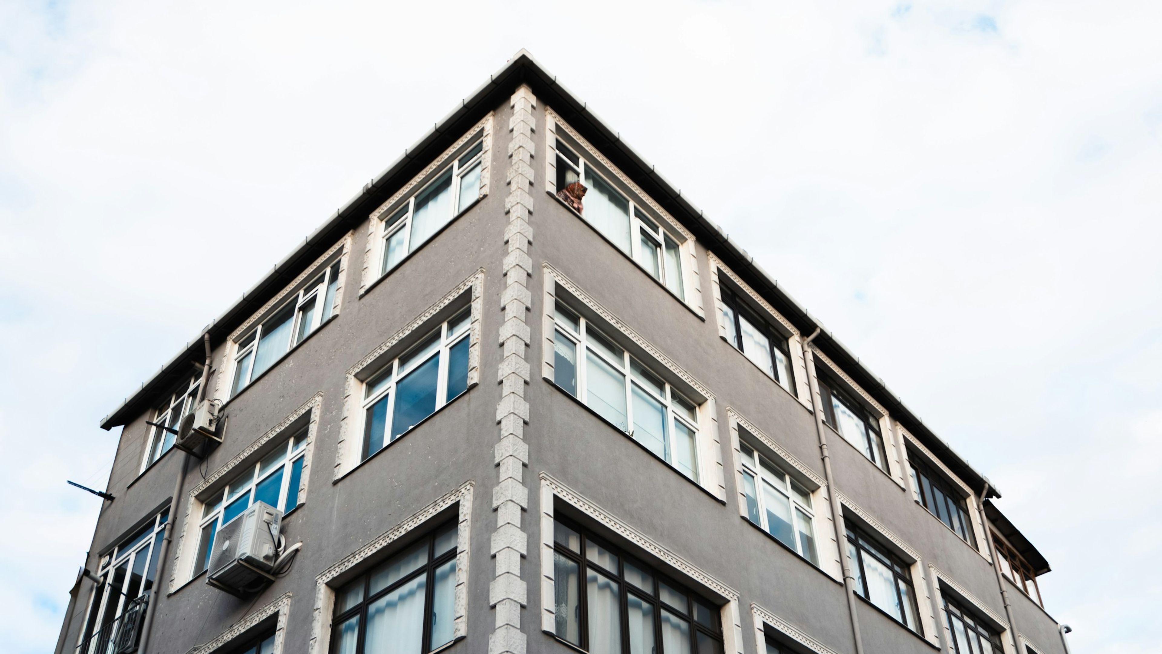 İstanbul'da çok pencereli bir apartmanın köşe cephesi, açık gökyüzüne karşı