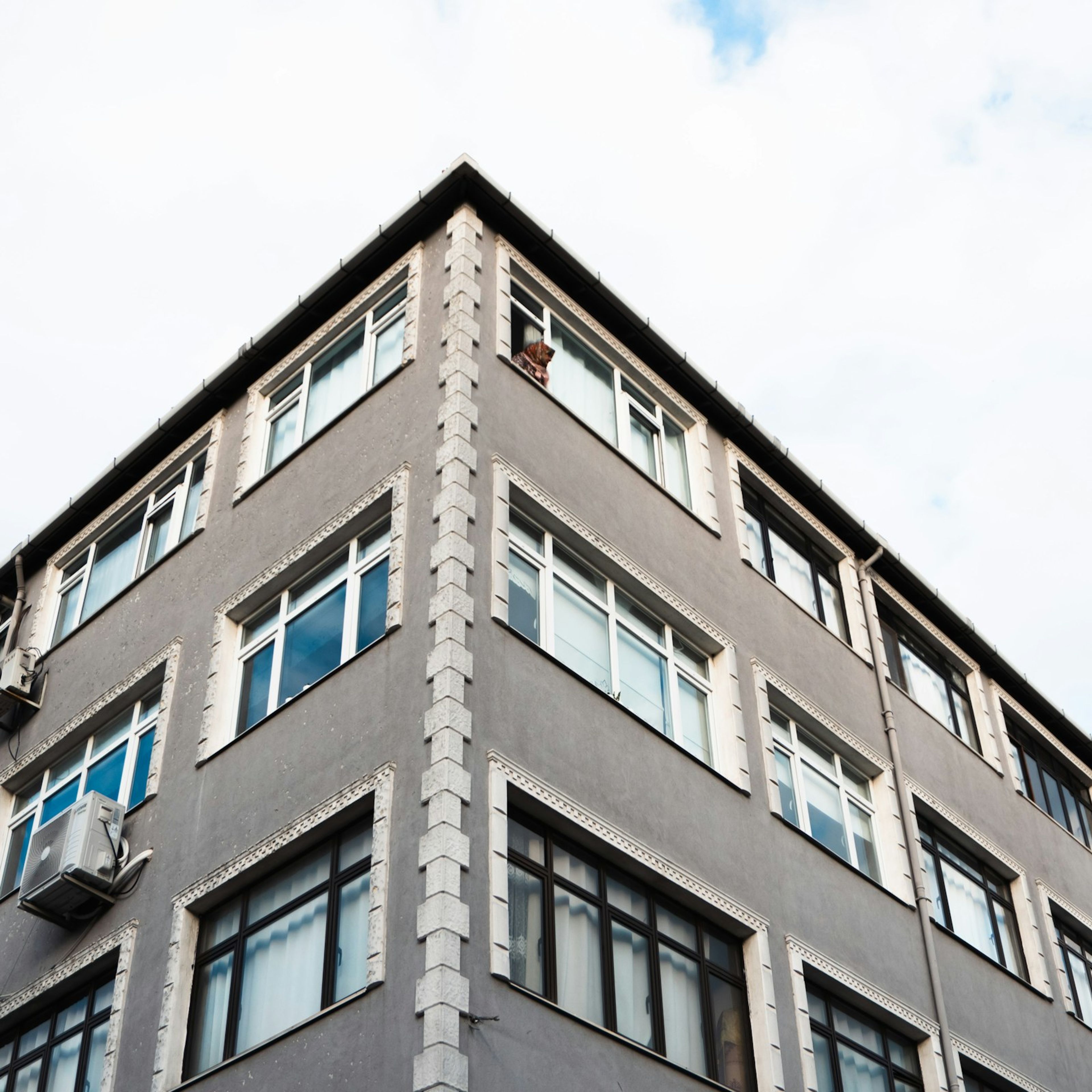 İstanbul'da çok pencereli bir apartmanın köşe cephesi, açık gökyüzüne karşı