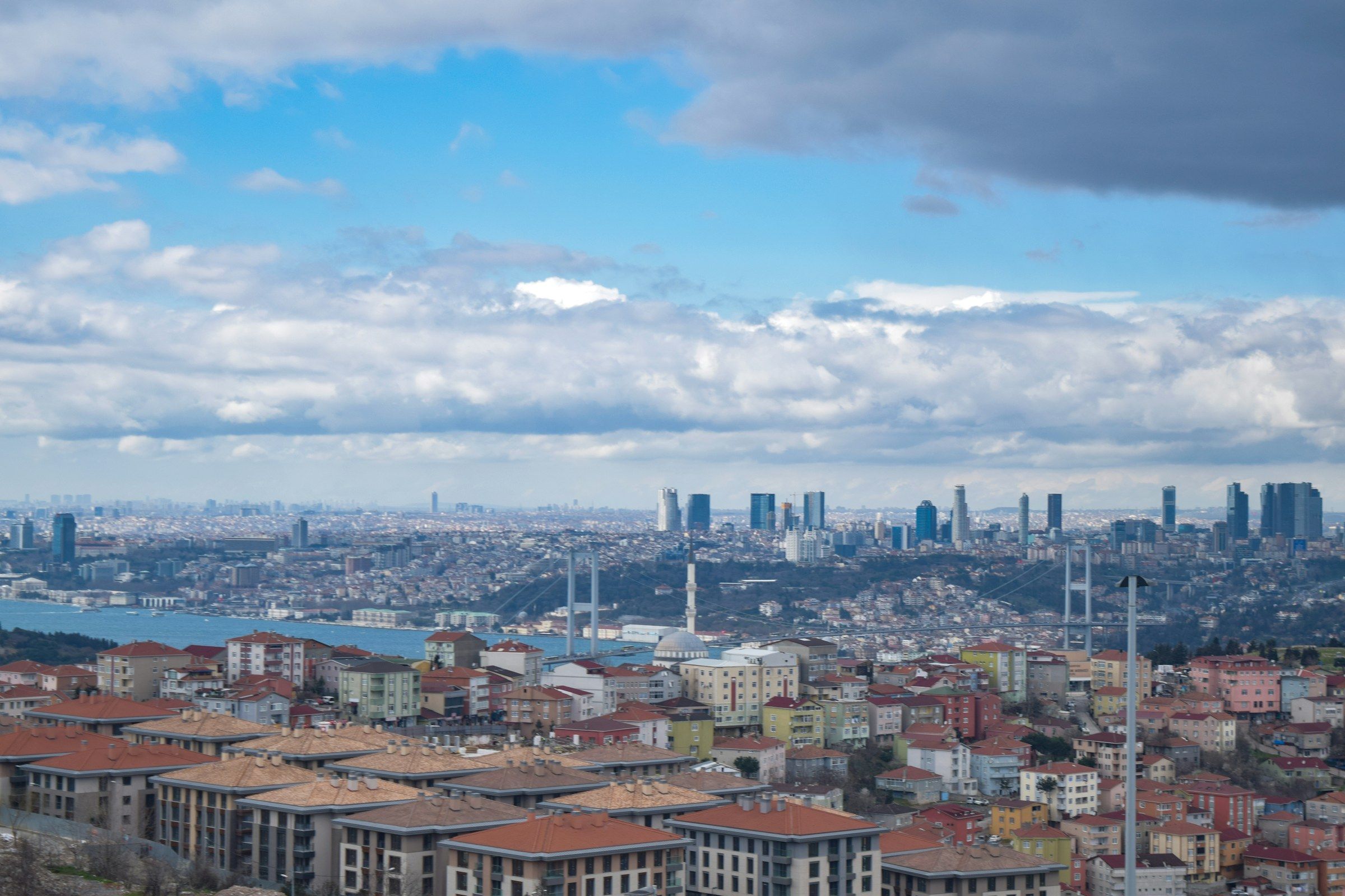 Boğaz köprüsü ve iki yakadaki konut dokusu, bulutlu gökyüzü altında