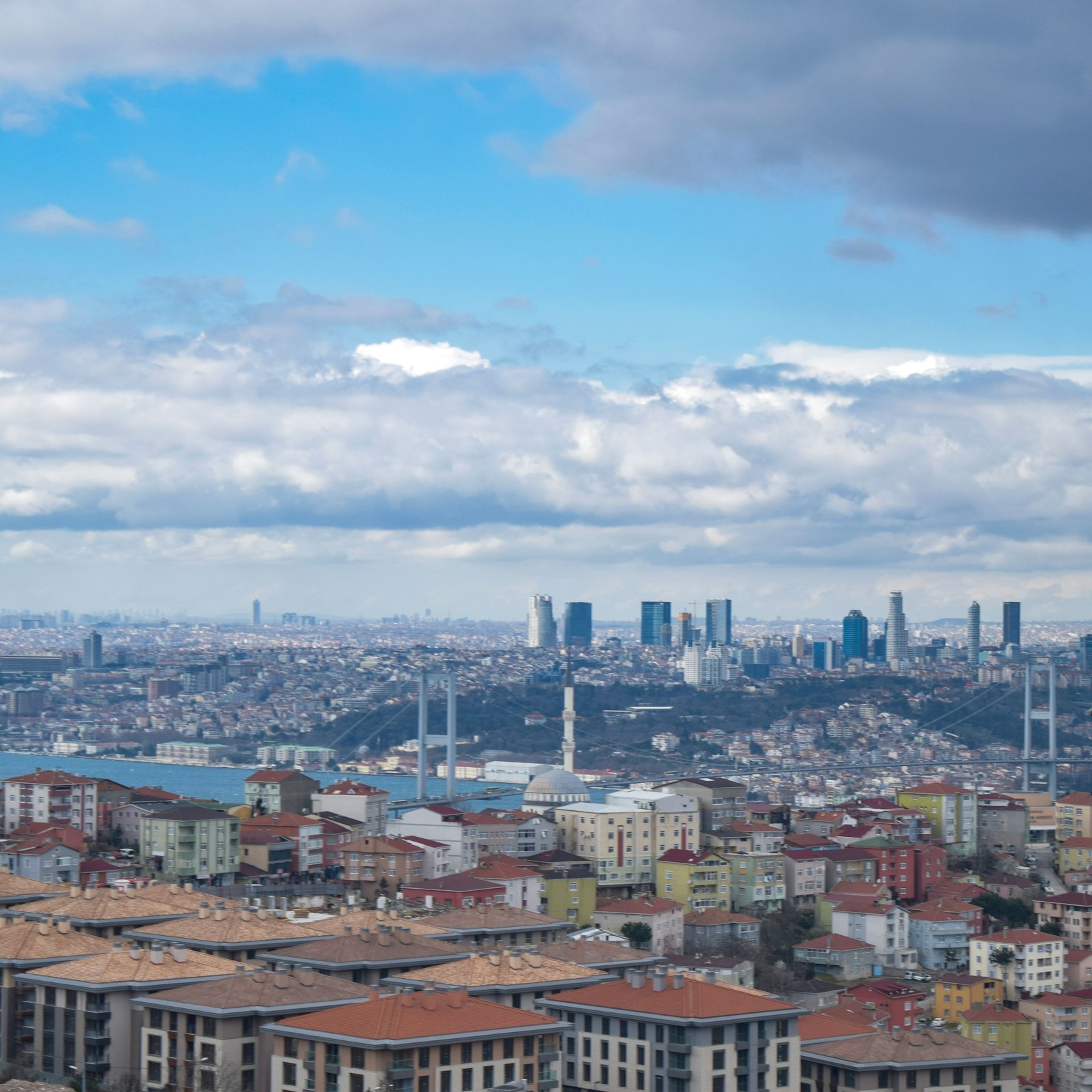 Boğaz köprüsü ve iki yakadaki konut dokusu, bulutlu gökyüzü altında