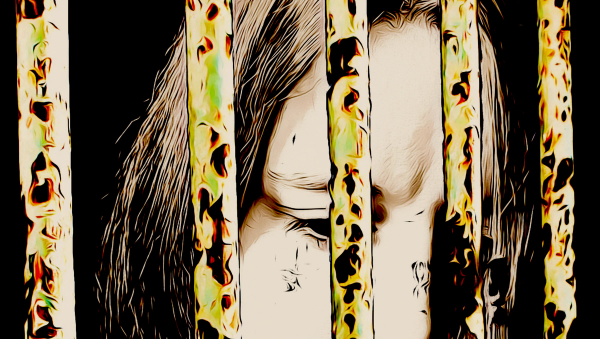 Closeup of a woman behind bars, gazing down sadly.