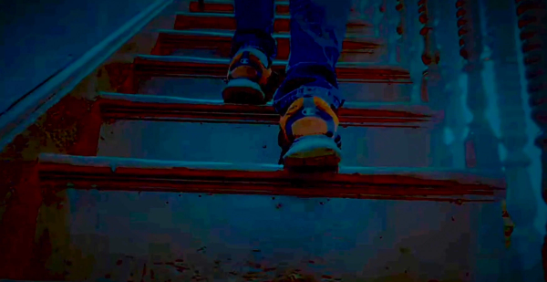 Closeup of heels of an intruder walking up a staircase, wearing bright orange shoes.
