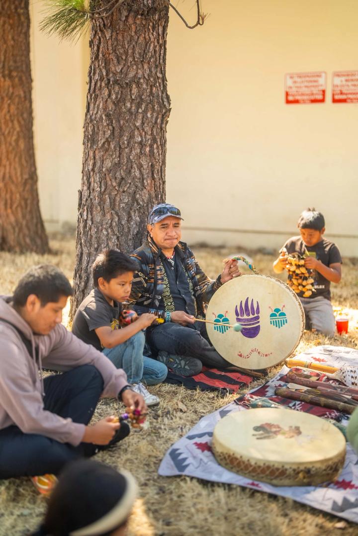 Community members sitting together outdoors beneath a tree