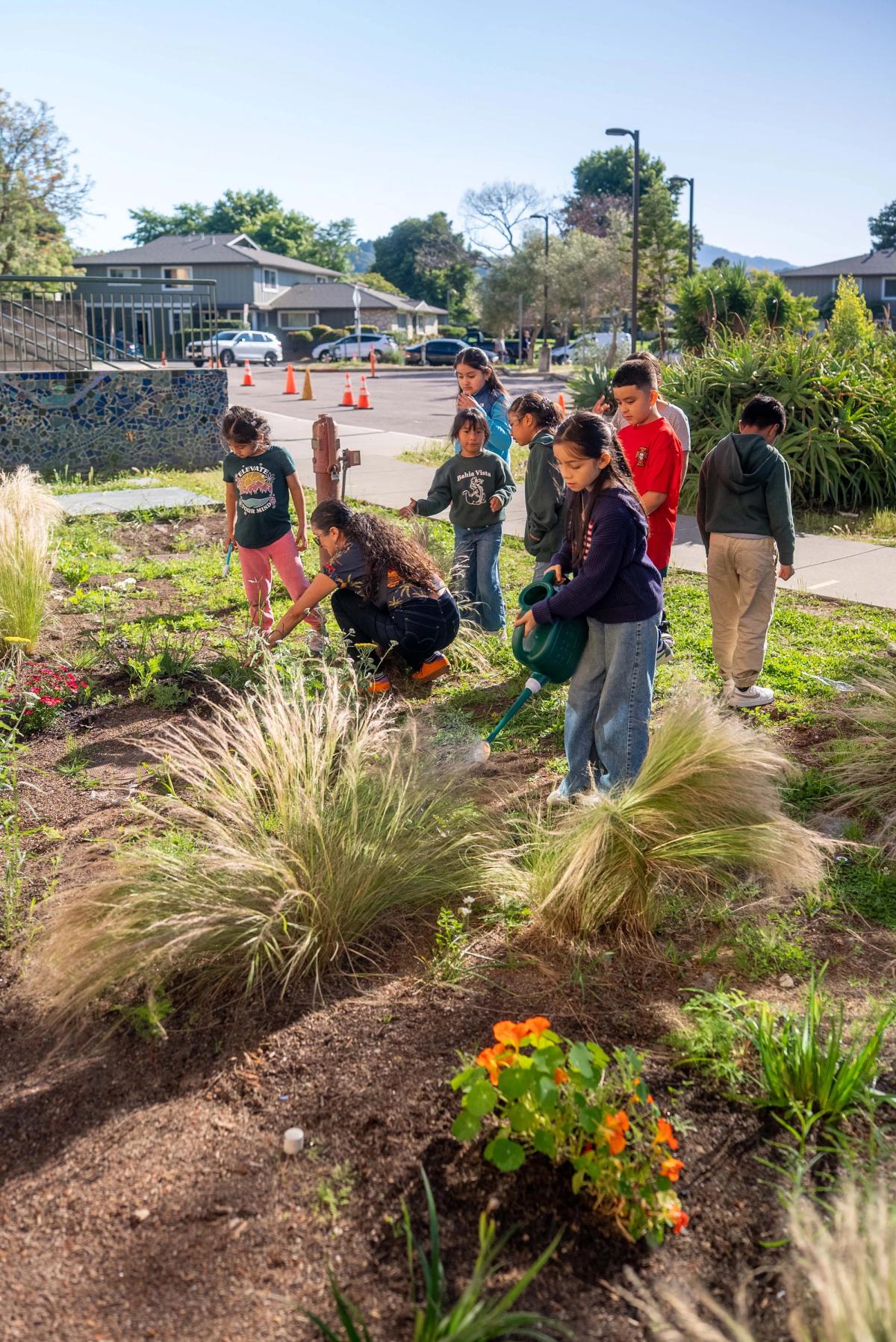 Students and an instructor gathered among flowering plants in the school garden