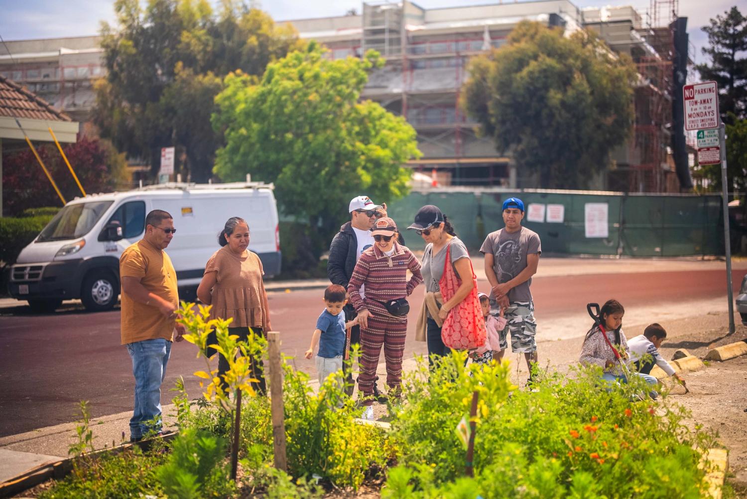 Students and adults gathered beside a flowering neighborhood garden
