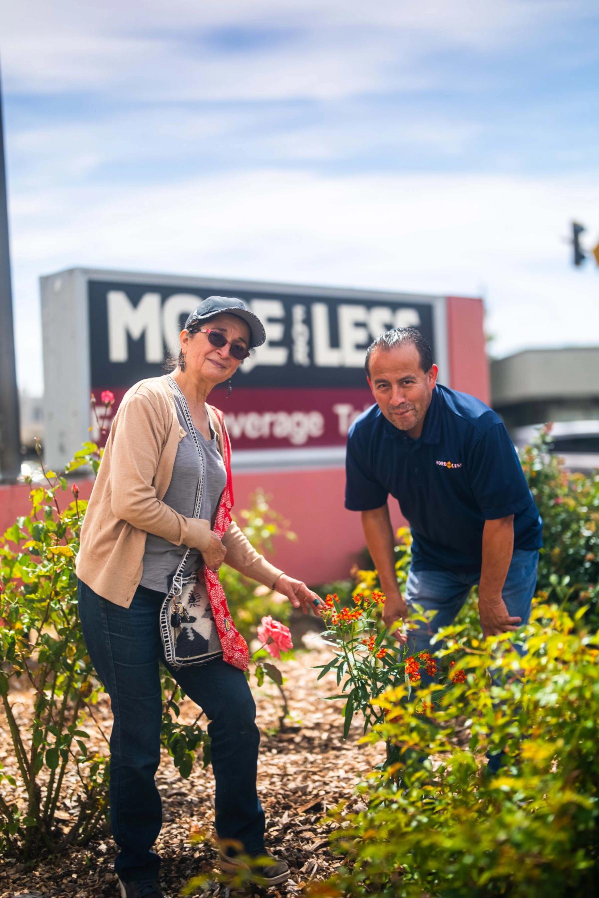 Two adults tending flowering plants in a neighborhood garden