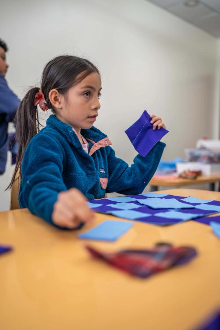 A child concentrating on a colorful craft project at a table