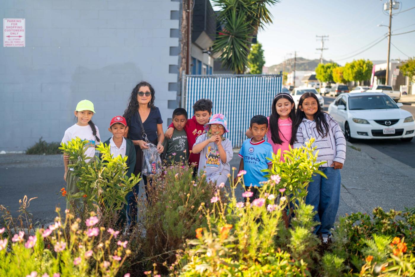 Young people and an adult standing together in a flowering neighborhood garden
