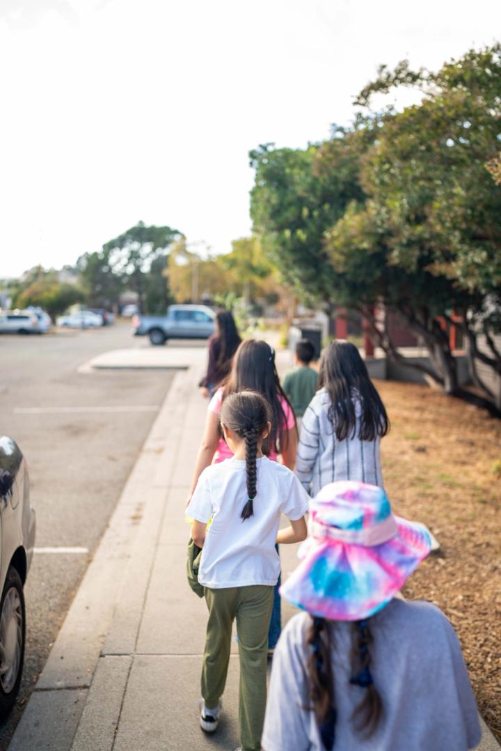 A group of children and adults walking along a neighborhood sidewalk