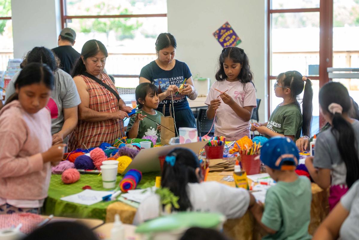 Children and adults making things together around a table of colorful craft materials