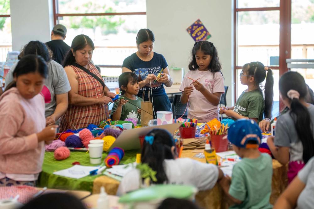 Young people and adults creating things at a Green Fest table in 2026