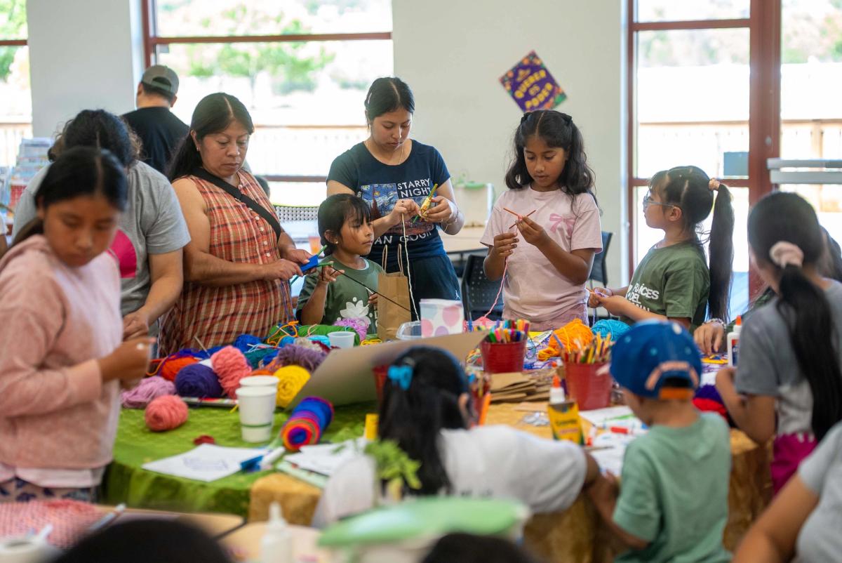 Children and adults making things together around a table of colorful craft materials