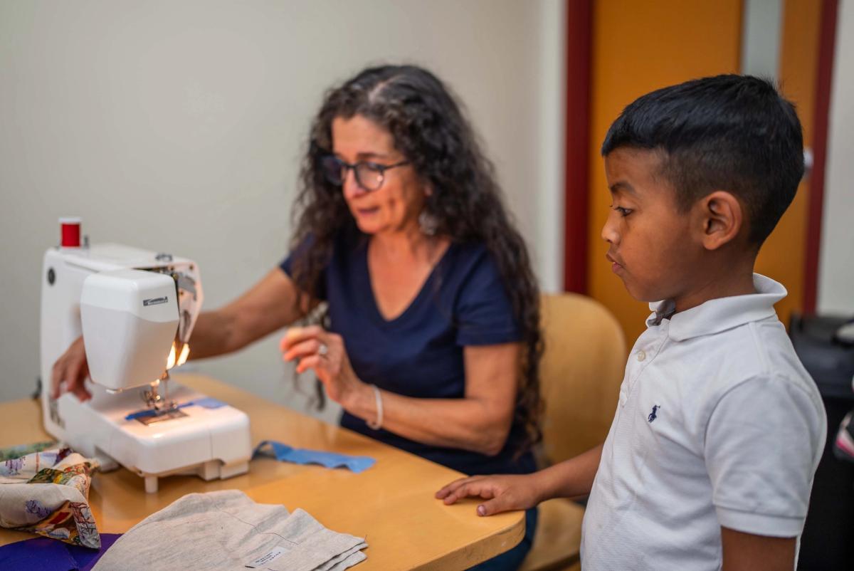 An instructor guiding a student beside a sewing machine