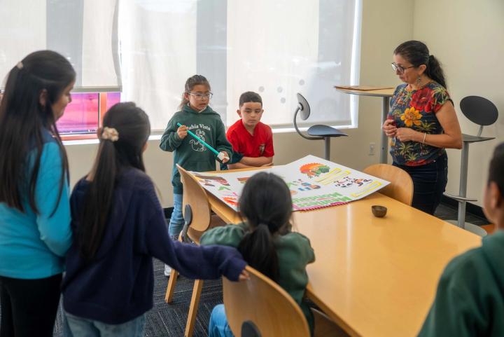 An adult and young people gathered around a table for a group activity
