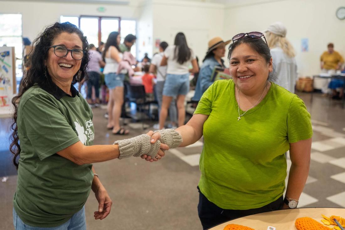 Two community members smiling and shaking hands at Green Fest