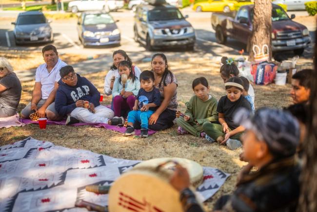 Community members sitting in a circle with a drum