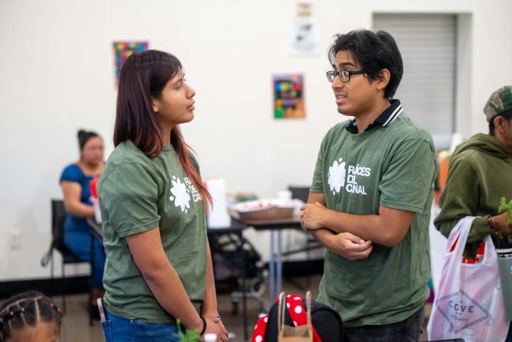 Two people talking beside an activity table at a community gathering