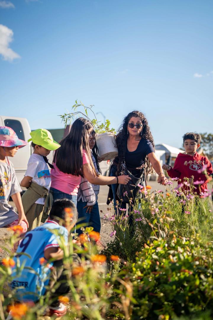 An adult and students looking closely at plants in a flowering neighborhood garden