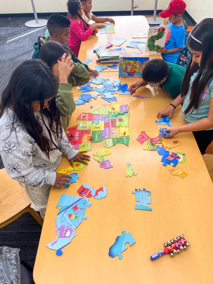 Young people and adults making colorful paper crafts around a long table