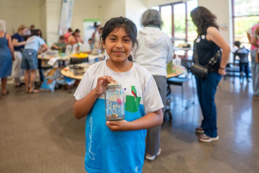 A smiling child holding a handmade project at a community event