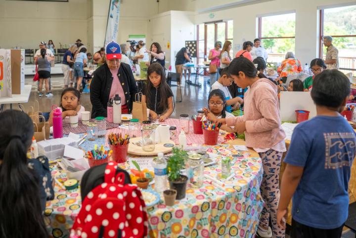 Families and community members gathering around colorful activity tables