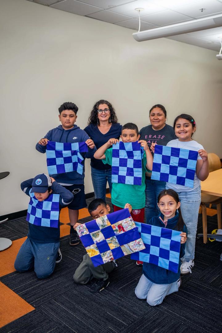Young people and an adult holding blue patchwork squares they have made