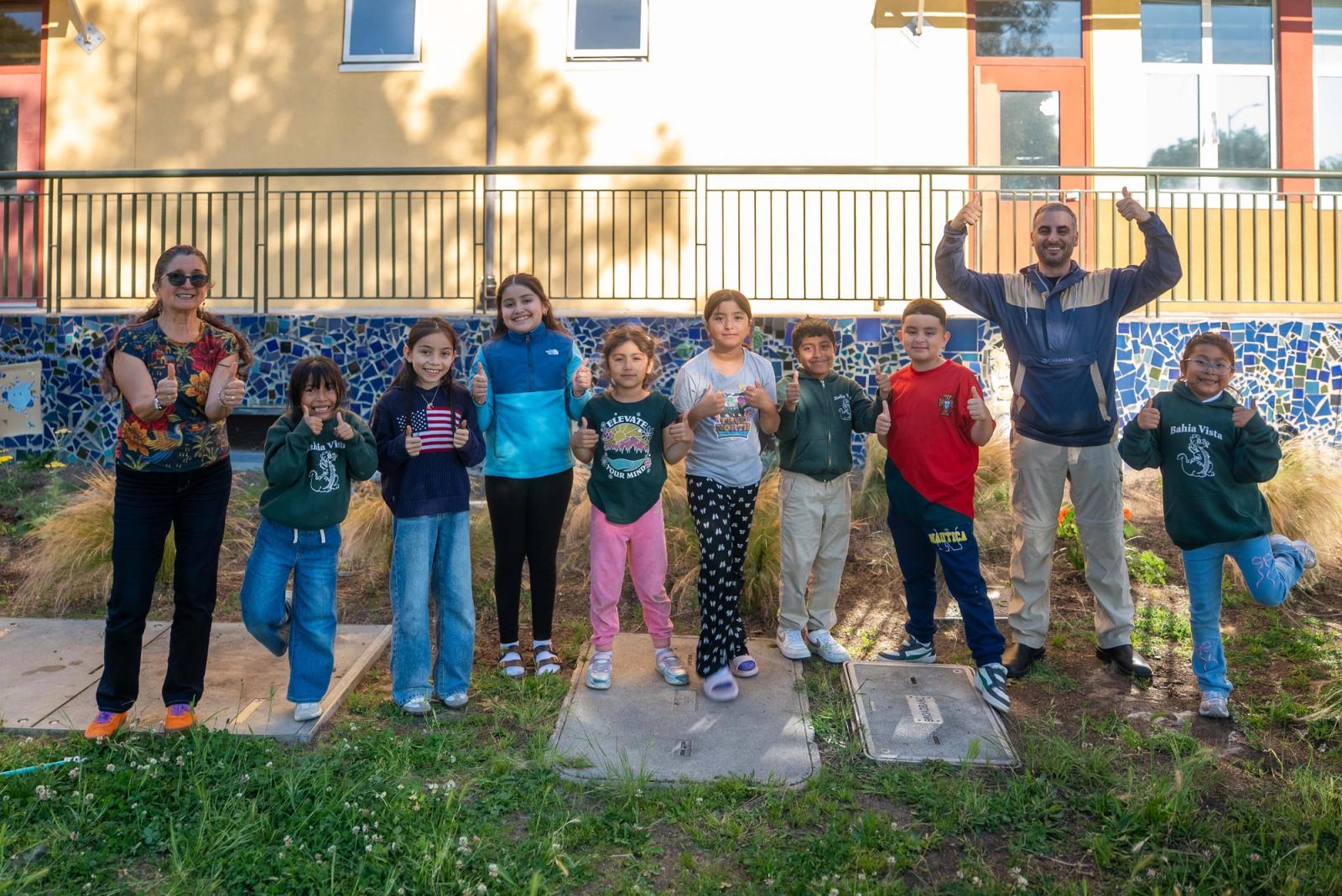 The Raíces del Canal student group and two instructors standing together beside the school garden