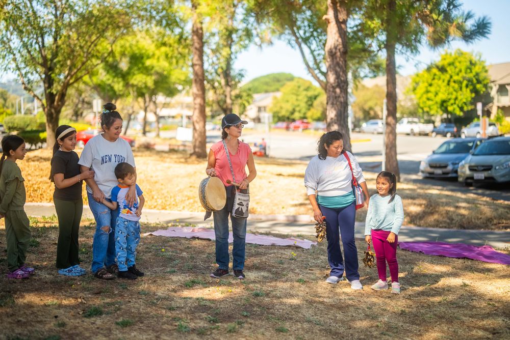 Children and adults standing together outdoors with drums