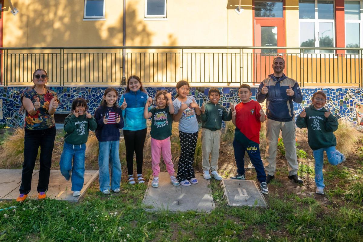 Students and their instructors posing together in front of the school building