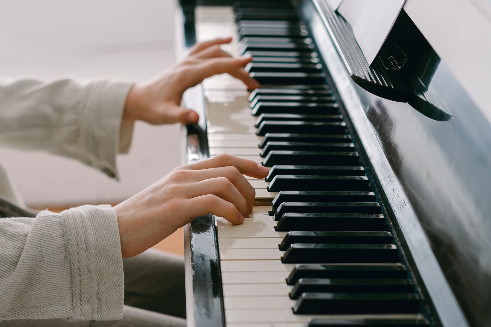 Mains d'un débutant jouant sur un piano numérique dans une pièce lumineuse