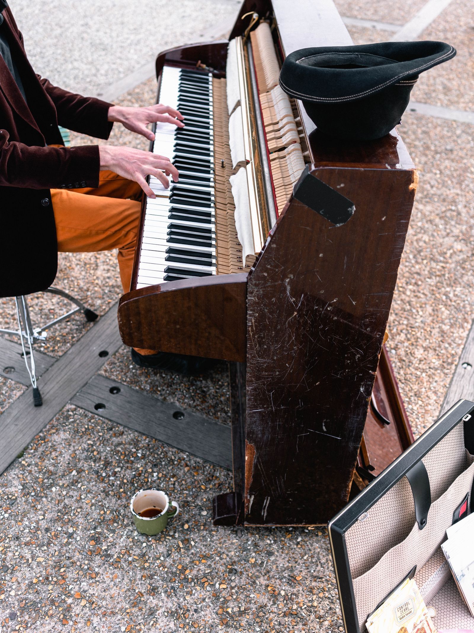 Piano droit installé en extérieur sur une place publique, joué par un musicien