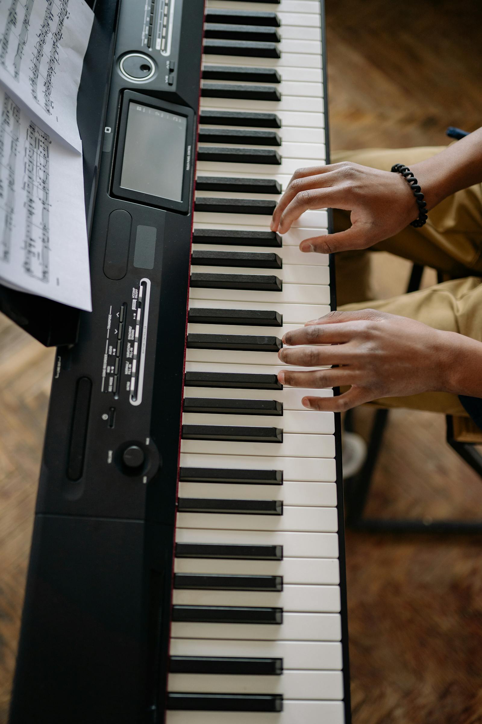 Mains posées sur un piano numérique affichant une partition à l'écran