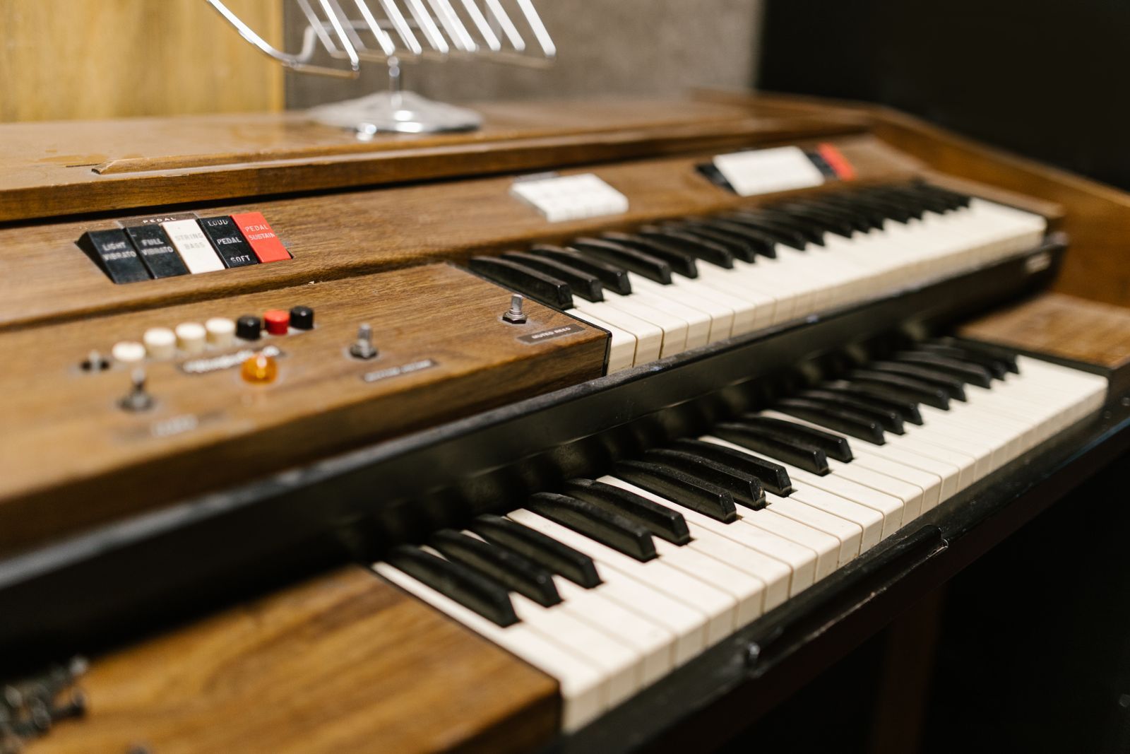 Gros plan sur un orgue et piano électrique à boiserie, claviers superposés et tirettes de registration
