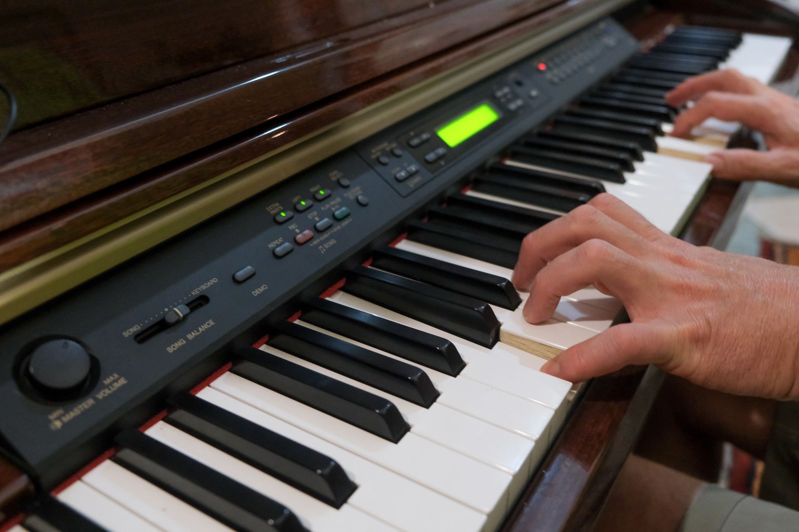 Mains jouant sur un piano numérique d'occasion doté d'un écran et de boutons