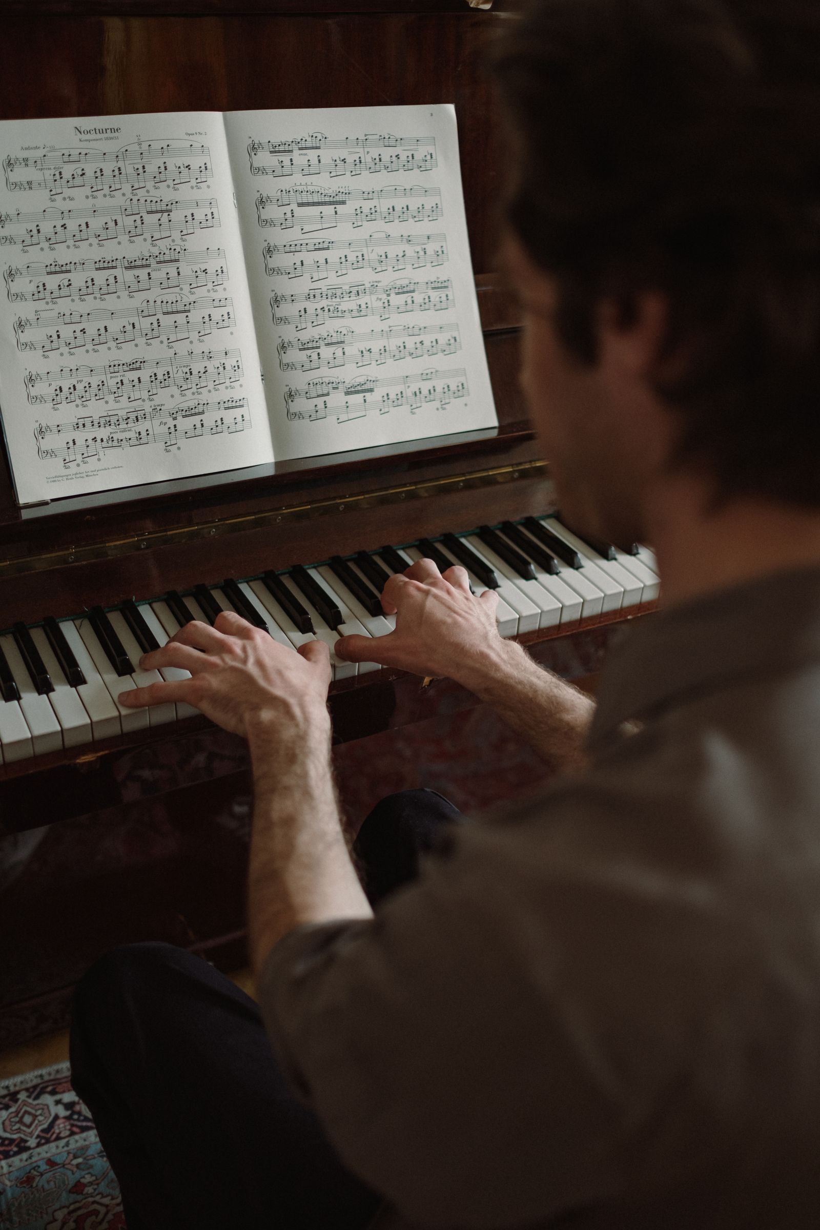 Personne jouant du piano chez elle en lisant une partition